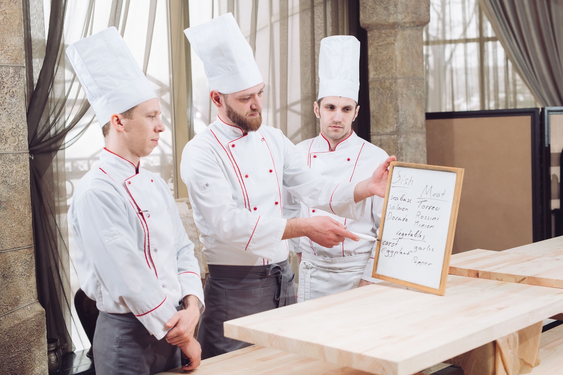 Küchenchef und seine Mitarbeiter in der Küche. Interaktion in der kommerziellen Küche.