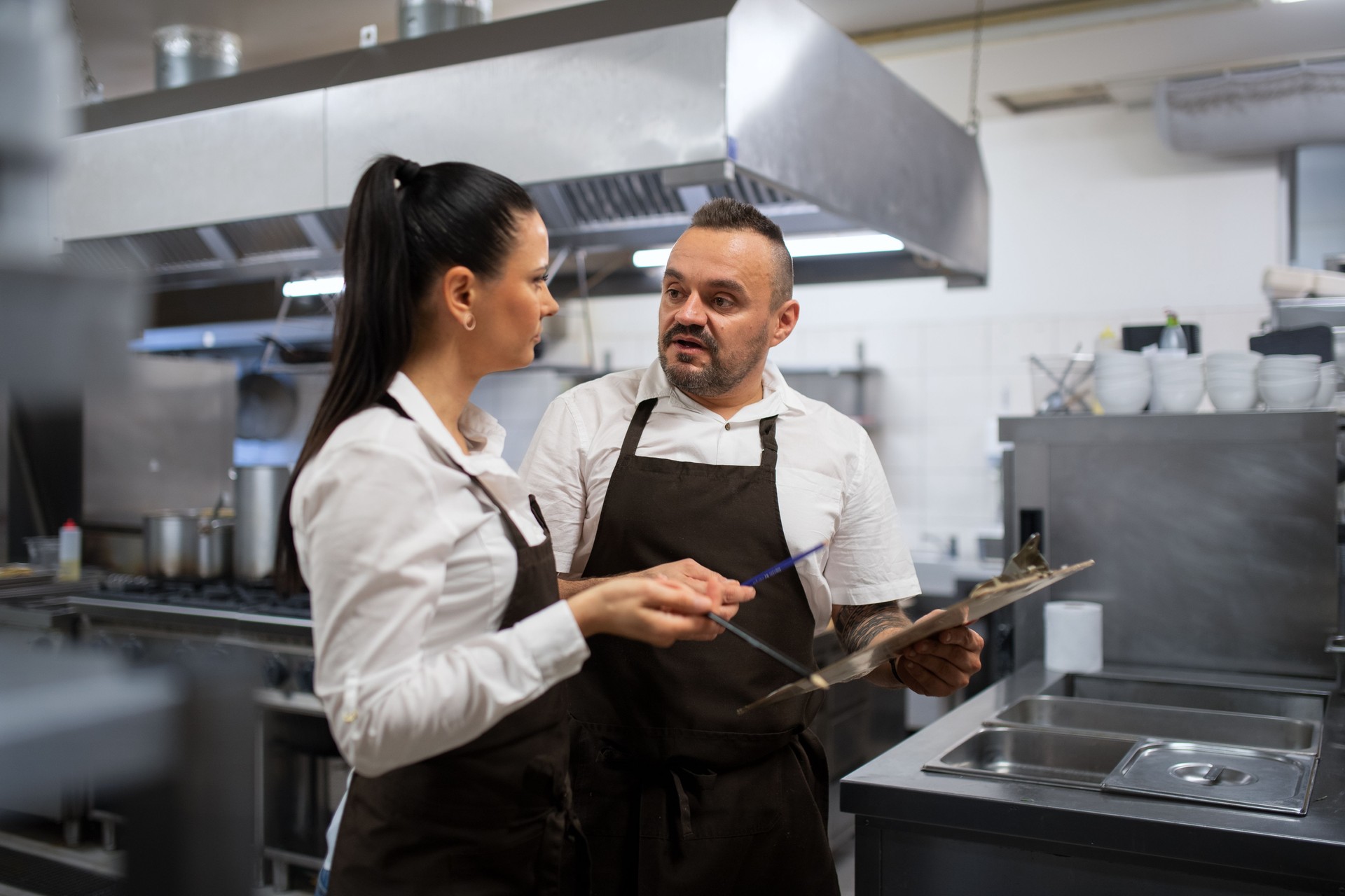 Koch und Koch diskutieren Menü drinnen in der Restaurantküche.